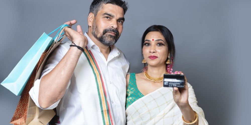 Indian couple in Ethnic wear with shopping bag and showing credit card towards the camera,Festival shopping concept